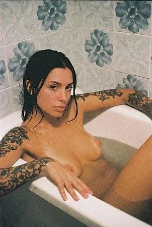 Tattooed girl posing in the bathtub